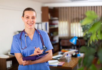 Portrait of friendly female doctor wearing uniform and stethoscope with folder