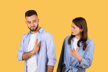 Man showing stop gesture to arguing woman, yellow background