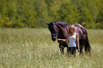 Woman young blonde long hair on a meadow in summer with horse.