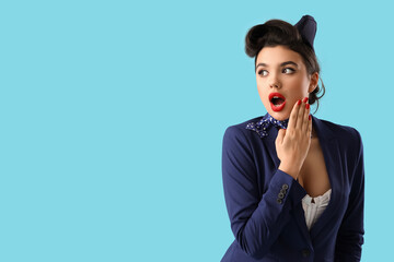 Shocked young pin-up stewardess on blue background