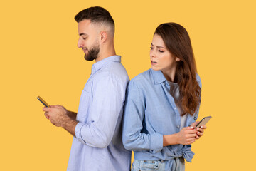 Curious woman peeking at man's phone screen, both holding smartphones