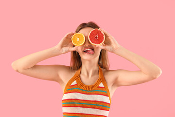 Funny young woman with citrus fruits on pink background