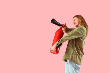 Young woman with fire extinguisher on pink background