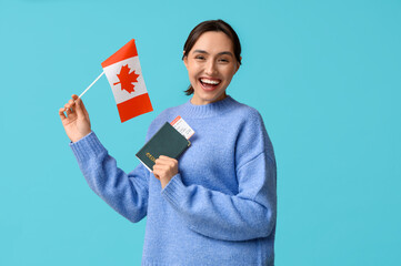 Pretty young woman with flag of Canada and passport on blue background. Immigration concept