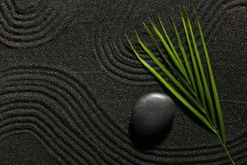 Stone and tropical leaf on dark sand with lines in Japanese rock garden, top view. Zen concept