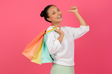 Cheerful Asian Female With Shopping Bags In Hand Showing Thumb Up Gesture