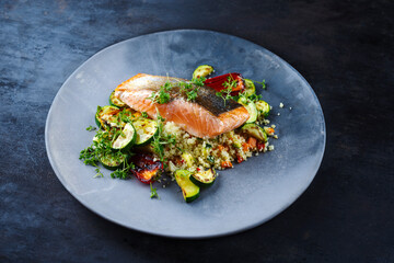 Traditional Mediterranean salmon fish fillet with vegetable cuscus served as close-up on a design...