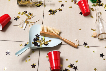 Dustpan with cleaning brush and mess on tile floor after party, closeup