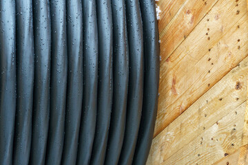 An electric cable in a polymer winding on a wooden coil. A high-voltage cable located on a construction site. Close-up of the cable bay. Optical fiber for the Internet.