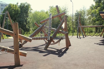 Wooden children playground made of natural eco-friendly material in public city park. Modern safety children outdoor equipment. Concept of sustainable lifestyle and ecology. Rest and games on open air