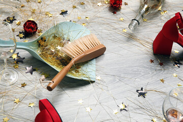 Dustpan with brush and mess on light wooden floor after party, closeup