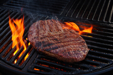 Traditional American barbecue flanksteak steak as close-up on a charcoal grill with fire
