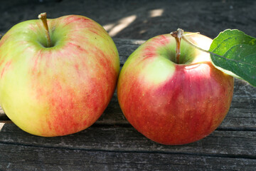 Two ripe apples with leaf lie on old wooden boards publication, poster, calendar, post, screensaver, wallpaper, postcard, banner, cover, website. High quality photo