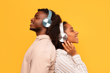 Couple enjoying music back-to-back with headphones