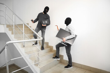 Male thieves with stolen valuables escaping in stairway