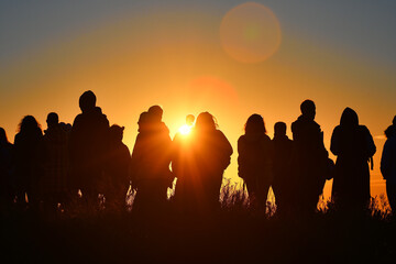 Fototapeta na wymiar Silhouettes of people greeting the first light of the day during the spring equinox