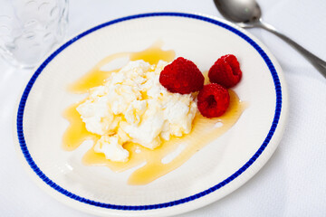 Catalan fresh cheese, mato, served with honey and raspberries on plate.