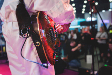 Concert view of an electric guitar player with vocalist and rock band performing in a club, male musician guitarist on stage with audience in a crowded concert hall arena, hands on a guitar - obrazy, fototapety, plakaty