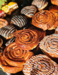 Pastry, selection assortment variety of different bakery, with cinnamon bun, croissant, swiss rolls, cake, eclair and others in a basket or a plate, baked desserts, catering or cafe banquet table