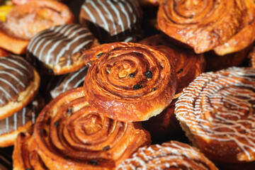 Pastry, selection assortment variety of different bakery, with cinnamon bun, croissant, swiss rolls, cake, eclair and others in a basket or a plate, baked desserts, catering or cafe banquet table
