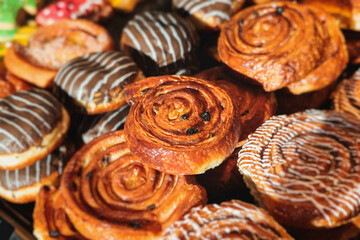 Pastry, selection assortment variety of different bakery, with cinnamon bun, croissant, swiss rolls, cake, eclair and others in a basket or a plate, baked desserts, catering or cafe banquet table