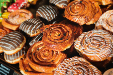 Pastry, selection assortment variety of different bakery, with cinnamon bun, croissant, swiss rolls, cake, eclair and others in a basket or a plate, baked desserts, catering or cafe banquet table