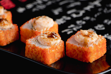 Sushi rolls with caviar on black plate. Serving Japanese food