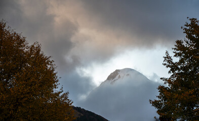 Snowy peak of Kazbek mountain covered evening low clouds seen from n Kazbegi, Stepantsminda, Georgia