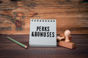 PERKS AND BONUSES. Cardboard notepad on wooden texture table
