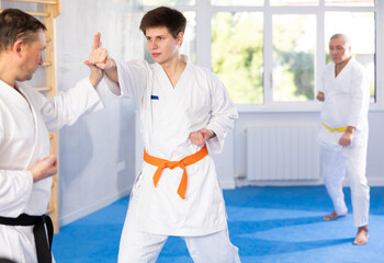 Obraz premium Adult man and young guy in kimono train karate fight in studio