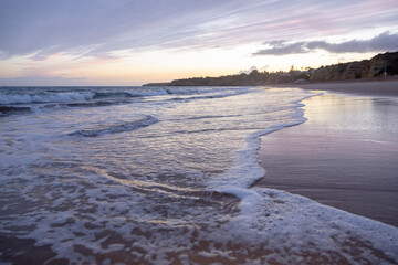 Soft wave crashing on sandy beach seaside in the evening. Summer vacation background concept. Algarve, Portugal