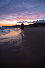 Naklejka premium Woman walking on the beach at sunset in the Algarve, Portugal.
