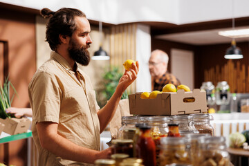 Man in zero waste store taking time to analyze fruits, making sure they are handpicked and farm...