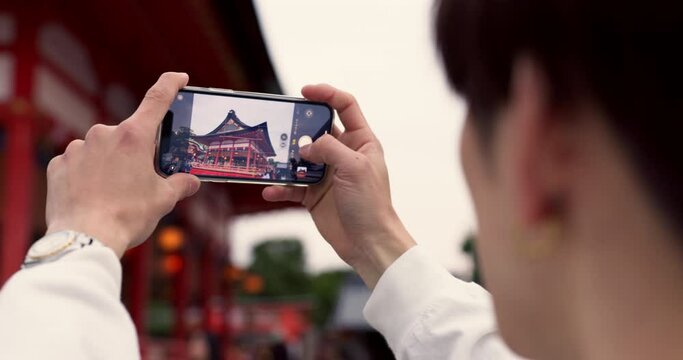 Phone, hands and tourist with picture in Japan on vacation, holiday trip or travel. Smartphone, person and closeup photography of Fushimi inari-taisha temple in Kyoto on mobile technology outdoor