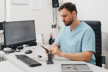 Otolaryngologist at modern medical center. Portrait of audiologist who assess disorders of hearing working with smartphone and computer. Copy space