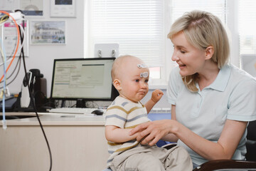 Woman with child consulting doctor for hearing checkup. Parent with infant kid visiting...