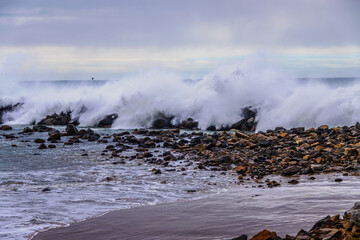 High surf waves crashing over breakwater