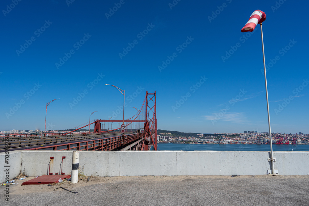 Wall mural windsock in operation with white background at the entrance of the 25 de abril suspension bridge in 