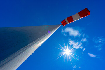 windsock in operation with strong blue sky background with sun