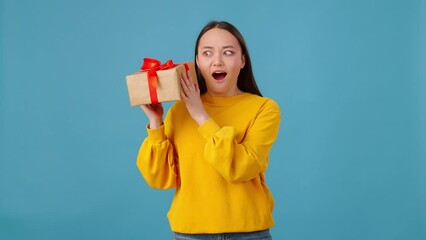 Female shaking gift box and trying to guess its contents