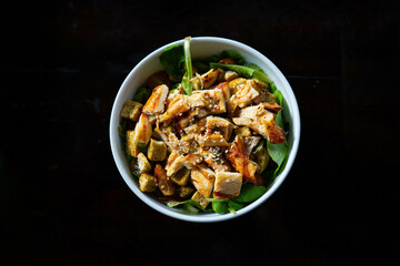 chopped chicken breast on top of caesar salad for lunch in white bowl at restaurant