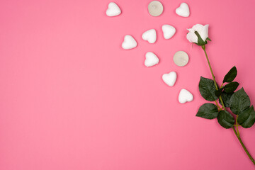 Romantic pink background with white roses with small white foam hearts and white candles