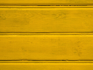 Wooden board of a wall or fence painted in rich saturated yellow color. Decorative element.