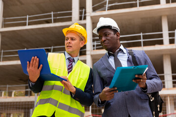 Architect and foreman must write documents and drawings on a laptop with building construction