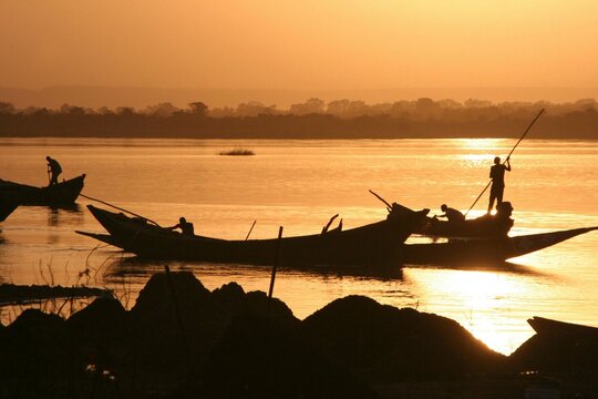 Pole barges on the Niger in the glow of the last sun at a jetty near Bamako, Mali, Africa