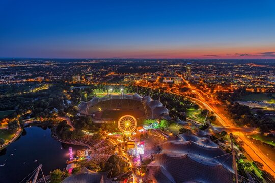 Munich from above at night with bright colours at sunset. View from the Olympic Tower during the Summer Festival, Germany, Europe