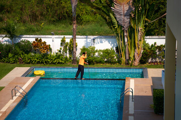 Top view of a worker cleaning a swimming pool in a private house in summer