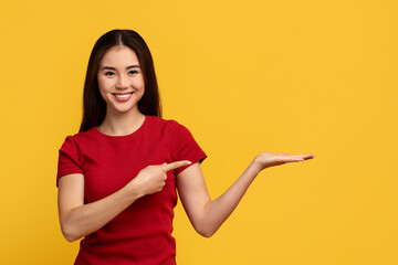 Cheerful asian woman pointing at copy space on her palm