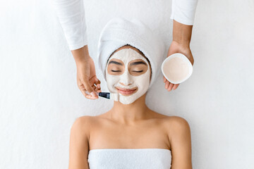 Captured in soothing setting, young indian woman enjoys facial mask