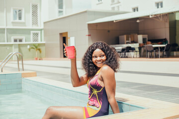 Smiling woman enjoying summer vacation, s at the swimming pool holding a red cup , sunbathing wellness Lifestyle concept.